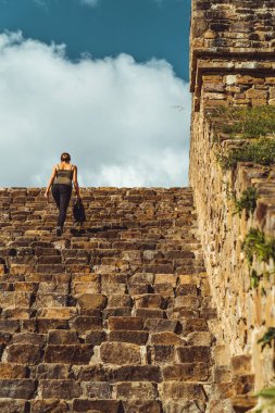 Palenque 'nin antik kalıntıları arasında, bir kadın yıpranmış merdivenlerden yükselir, varlığı tarihin ebedi ruhunun bir kanıtıdır, geçmiş ve şimdiki zaman her adımla iç içe geçer.
