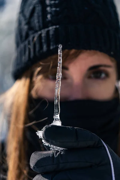 stock image A woman delicately holds a frozen water shape, its intricate patterns reflecting in her curious eyes.