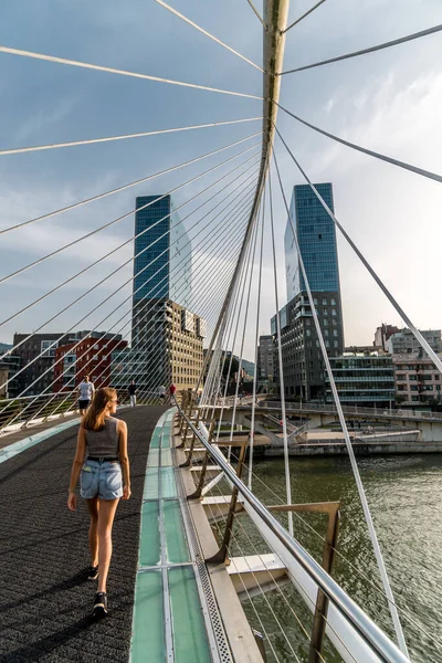 stock image A woman gracefully crossing a modern bridge in Bilbao, the city's architectural marvel blending elegance and functionality.