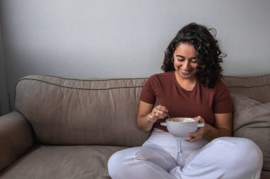 Sağlıklı bir kahvaltı yaparken gülümseyen kıvırcık saçlı kız. Boşluğu kopyala