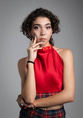 Kıvırcık saçlı kız bir stüdyoda fotoğraf çekimi sırasında kameraya bakar.