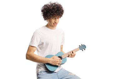 Beyaz arka planda ukulele çalan kıvırcık saçlı genç adam.