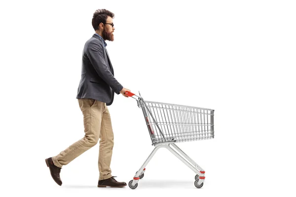 白地に隔離されたショッピングカートを押す髭の男の完全な長さのプロフィールショット — ストック写真