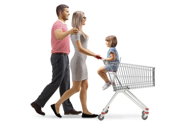 白い背景に隔離された子供とショッピングカートを押しているカップルの完全な長さのプロフィールショット — ストック写真