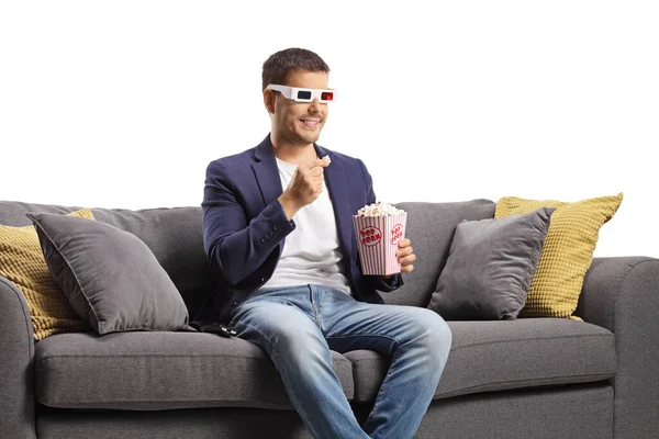 戴著3D眼镜的年轻人吃爆米花 坐在白色背景的沙发上 — 图库照片