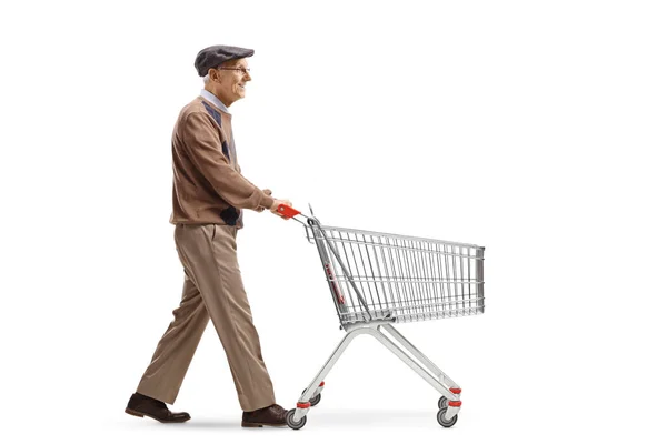 白い背景に隔離された空のショッピングカートを押して歩く高齢者の完全な長さのプロフィールショット — ストック写真