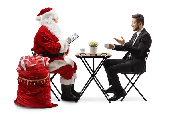 圣诞老人写了一份文件 和一个有着白人背景的商人坐在一张桌子旁 — 图库照片