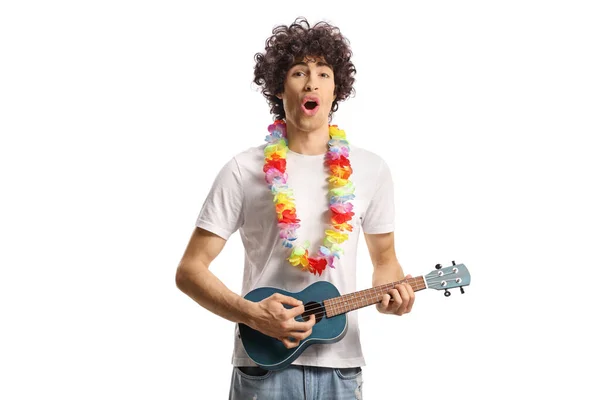 Young man with flower chain around neck playing ukulele isolated on white background