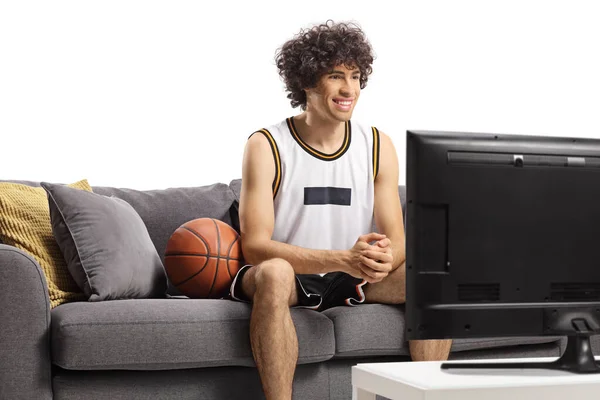 バスケットボール選手はソファに座って白い背景に隔離されたテレビを見て — ストック写真