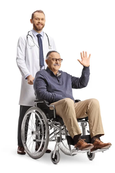 白い背景に隔離された車椅子に座って手を振っている成熟した男の後ろに立っている医者 — ストック写真