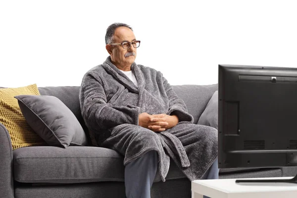 Зрелый Мужчина Халате Сидит Сером Диване Смотрит Телевизор Белом Фоне — стоковое фото