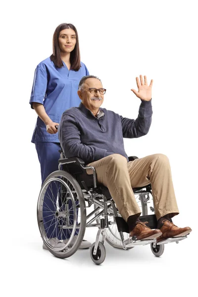 白い背景に隔離された車椅子に座って手を振っている熟年の男の後ろに立つ看護婦 — ストック写真