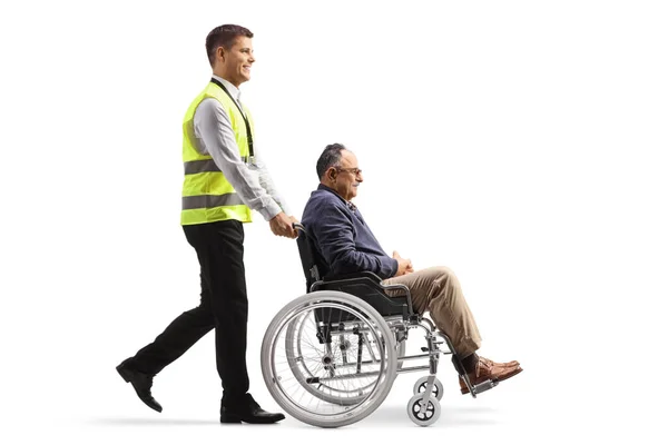 白地に隔離された車椅子で成熟した男を押す空港支援労働者の全長プロファイルショット — ストック写真