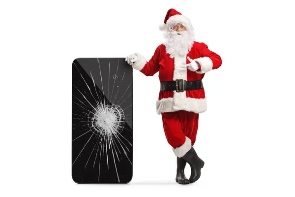 Święty Mikołaj Wskazując Smartfona Pękniętym Ekranem Odizolowany Białym Tle — Zdjęcie stockowe