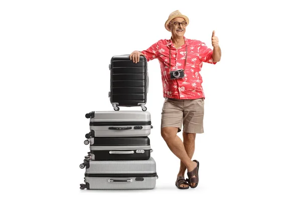 一个成熟男子靠在一堆手提箱上的全长肖像 显示出被白色背景隔离的大拇指 — 图库照片