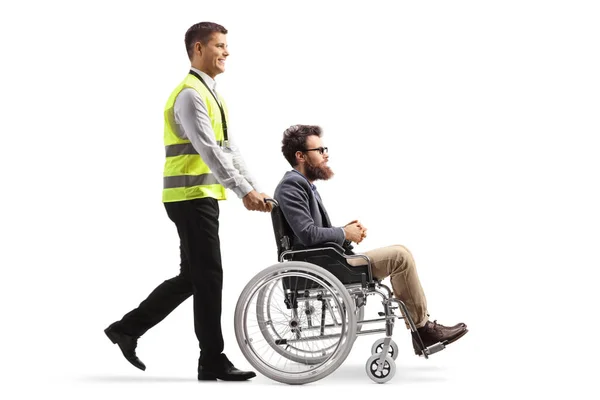 白地に隔離された車椅子に男を押し込む空港労働者の全長プロファイルショット — ストック写真