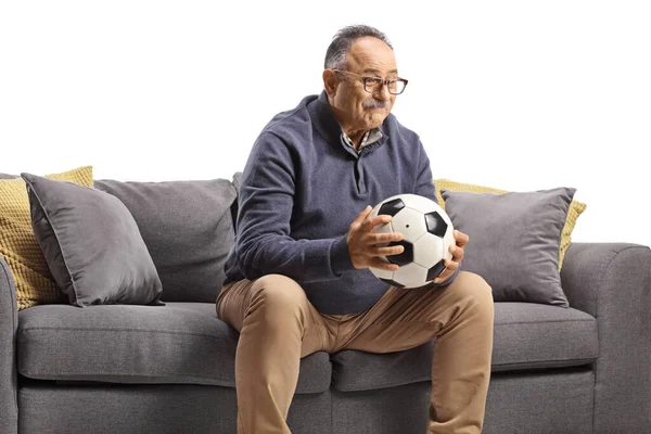 Reifer Mann Sitzt Auf Einem Sofa Und Hält Einen Fußball — Stockfoto