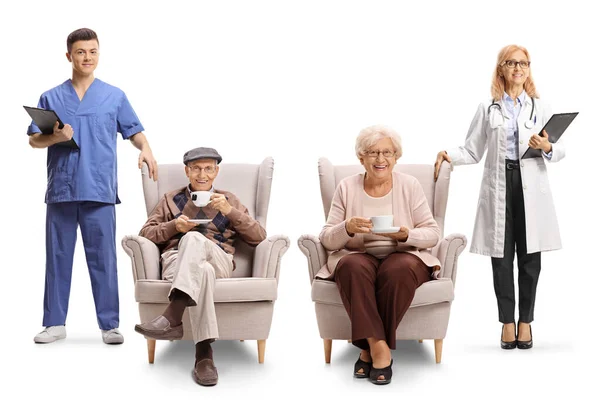 白い背景で隔絶されたアームチェアに座っている高齢男性と女性の世話をする女性医師と男性看護師 — ストック写真
