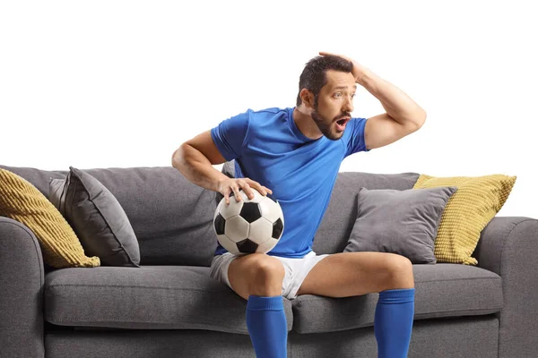 Surpreendido Atleta Masculino Sentado Sofá Segurando Uma Bola Futebol Segurando — Fotografia de Stock