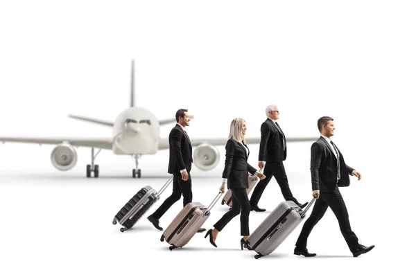 白い背景に隔離された駐車中の飛行機の前を歩き スーツケースを引っ張るビジネスマン — ストック写真
