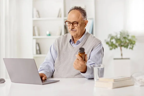 Dojrzały Mężczyzna Siedzi Przed Laptopem Trzyma Butelkę Tabletek Domu — Zdjęcie stockowe
