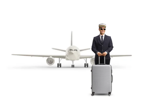 白い背景に隔離された飛行機の前にスーツケースを着た若いパイロット — ストック写真