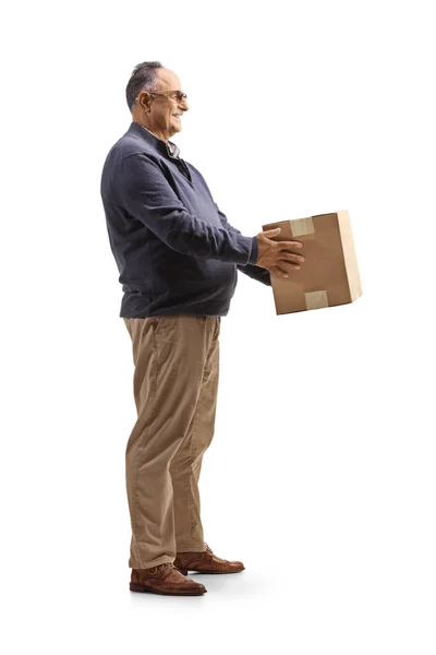 白い背景に隔離された段ボール箱を持っている成熟した男の完全な長さのプロフィールショット — ストック写真