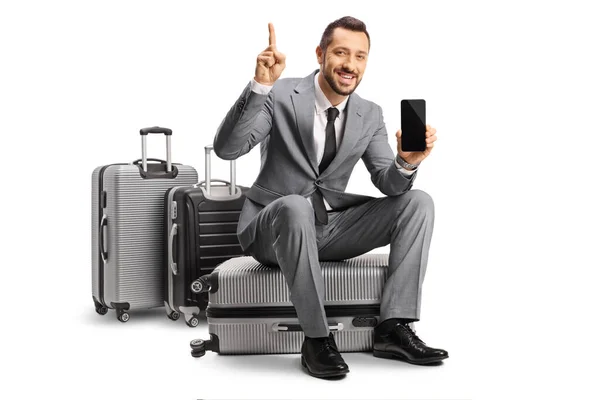 Bussinessman Sitting Suitcase Pointing Showing Smartphone Isolated White Background — Stock Photo, Image