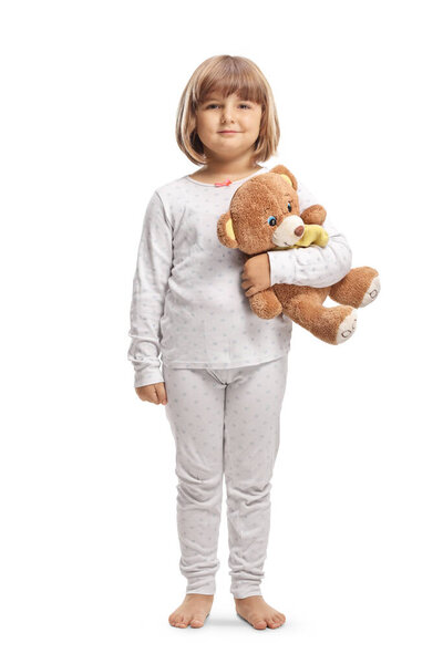 Full length portrait of a little girl in pajamas holding a teddy bear isolated on white background