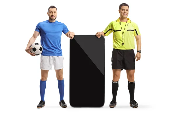 一个足球运动员和一个裁判站在一个白色背景的大智能手机旁边的全长肖像 — 图库照片