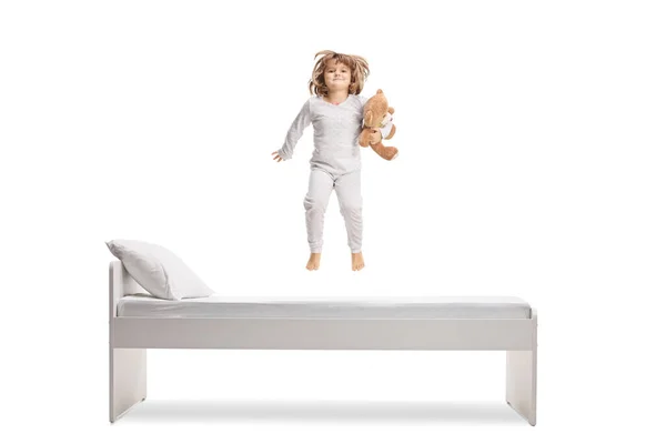 Маленькая Девочка Пижаме Держит Плюшевого Медведя Прыгает Кровати Изолированы Белом — стоковое фото