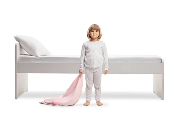一个穿着睡衣 拿着粉色毯子的小女孩的全长肖像 她的床被白色的背景隔开了 — 图库照片