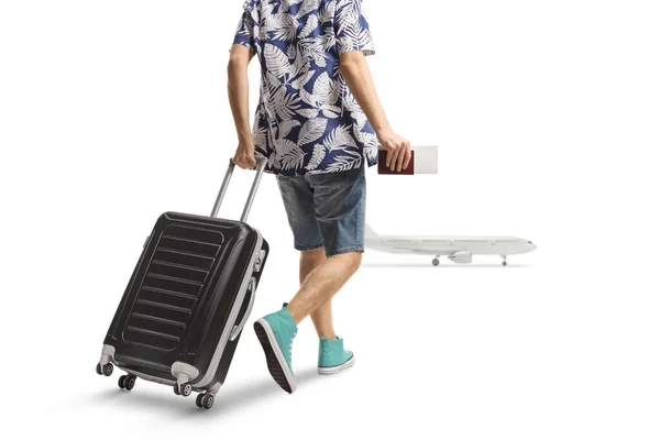スーツケースを引っ張り白い背景に隔離された飛行機に向かって歩く男性の乗客の後部ビューショット — ストック写真