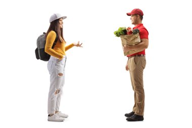 Sırt çantalı bir kız öğrencinin, beyaz arka planda izole edilmiş market çantalı bir teslimatçıyla konuşurken tam boy profil fotoğrafı.
