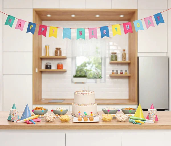 Kitchen decorated for a birthday party with cake and snacks on a wooden counter