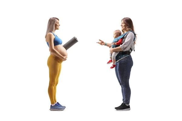 一名穿着运动服的孕妇穿着运动服 带着运动垫 与一位因白色背景而被隔离的母亲和婴儿进行对话 照片全长 — 图库照片