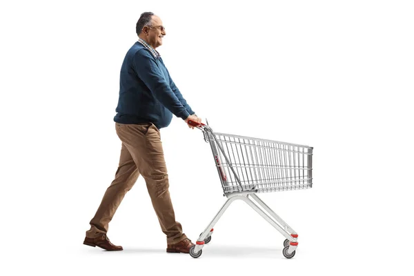 成熟した男の完全な長さのプロフィールショット歩くと白い背景に隔離された空のショッピングカートを押す — ストック写真
