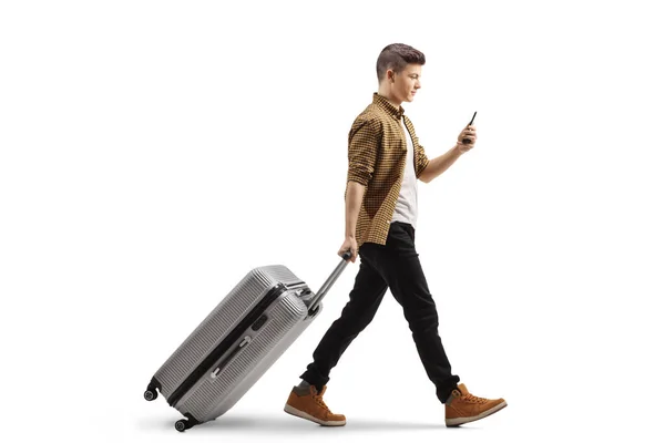 白い背景に隔離されたスーツケースを引っ張るスマートフォンを持つ男の完全な長さのプロフィールショット — ストック写真