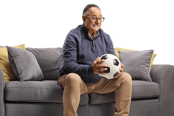 Зрелый Мужчина Держащий Футбольный Мяч Сидящий Диване Белом Фоне — стоковое фото