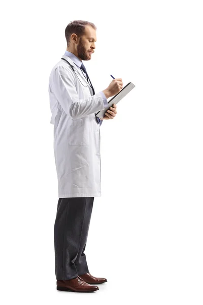 男性医師立ちの完全な長さプロファイルショットと白の背景に隔離された文書を書く — ストック写真