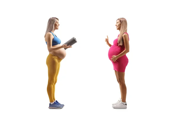 穿着运动服的孕妇 带着锻炼垫 与另一个因白人背景而被隔离的孕妇交谈 — 图库照片