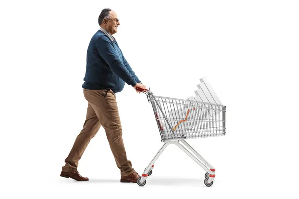 成熟した男の完全な長さのプロフィールショット歩くと白の背景に隔離されたバーチャートとショッピングカートを押す — ストック写真