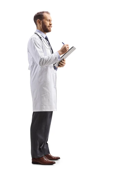 一名男性医生站在那里 用白色背景写下一份文件的全长照片 — 图库照片
