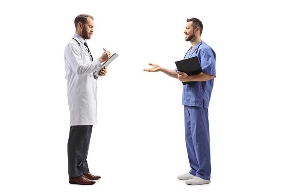 白い背景に隔離された医療従事者との文書や会話を立っている男性医師の完全な長さのプロフィールショット — ストック写真