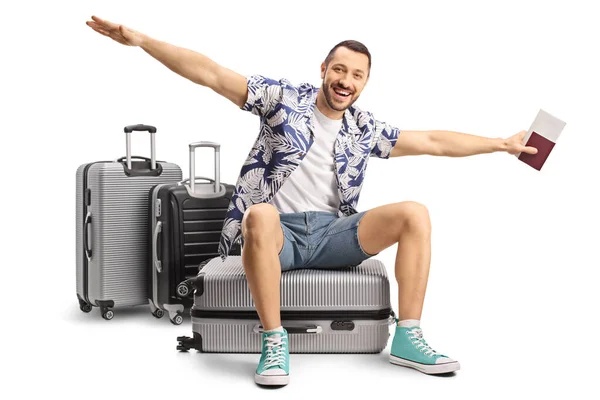 男性の観光客はスーツケースに座って白い背景に隔離された飛行する腕を広げる — ストック写真