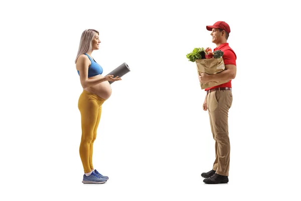 一个孕妇拿着一个白色背景的购物袋和一个送货员交谈时的全长照片 — 图库照片
