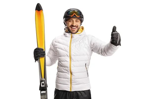 快乐的男性滑雪者拿着滑雪板 把大拇指伸出来 被白色的背景隔开 — 图库照片