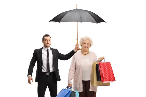 Leibwächter Mit Regenschirm Für Eine Ältere Frau Mit Einkaufstaschen Auf — Stockfoto