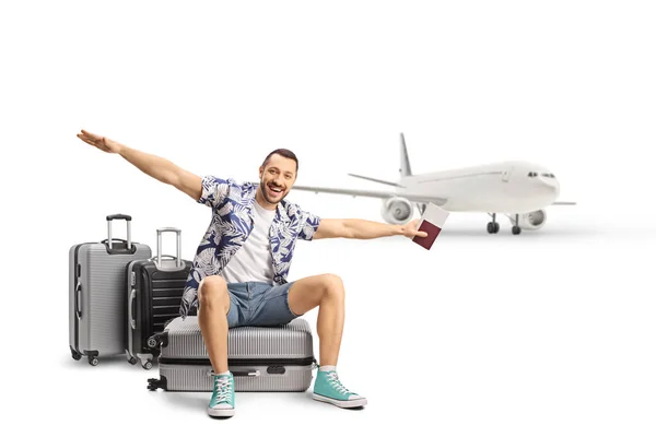 飞机和一名男性游客坐在行李箱上 张开双臂 在白色背景下独立飞行 — 图库照片