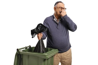 Olgun bir adam beyaz arka planda izole edilmiş bir çöp kutusuna kokulu bir çanta atıyor.